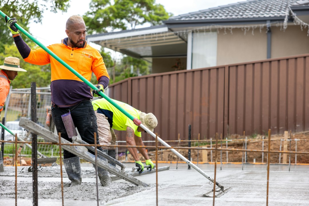 Construction workers finishing concrete work on a site; tradies should review general liability insurance for worksite risks.